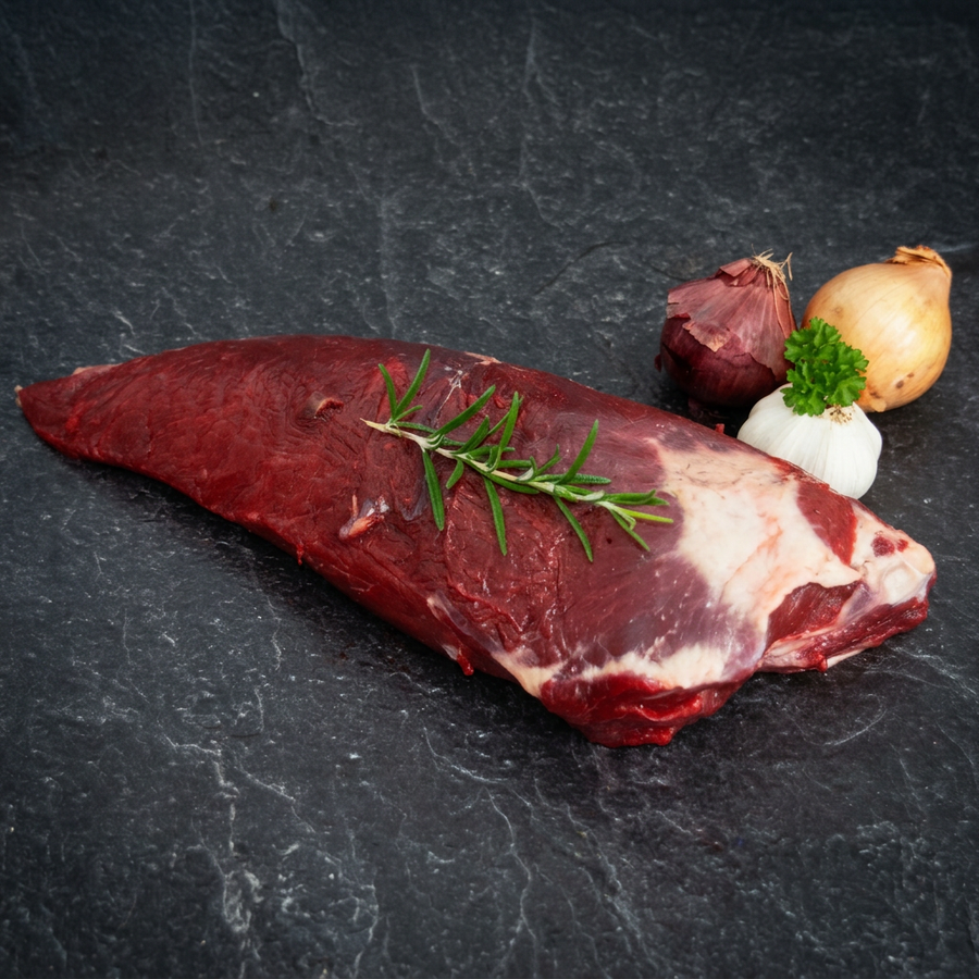 Rohes falsches Filet vom Rind mit einem Rosmarinzweig auf dunklem Steinuntergrund.
